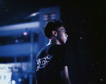 Side view of young man looking away at night