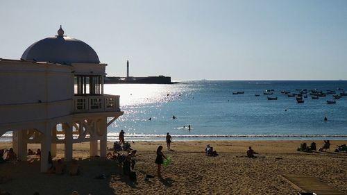 People at beach against clear sky during summer