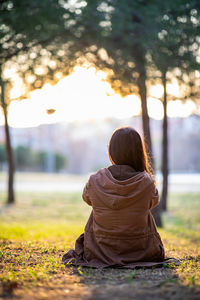 Rear view of woman sitting on land