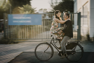 Man riding bicycle with woman sitting on handle