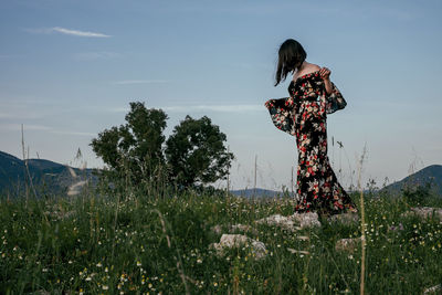 Woman standing on field against sky