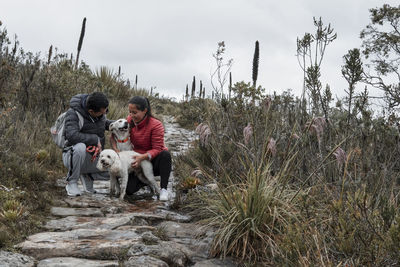 Young couple with two dogs on stone in the filed  through sustainable outdoors activity