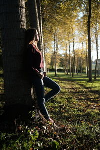 Girl leaning on tree in forest