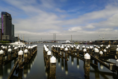 Boats moored in harbor by buildings against sky