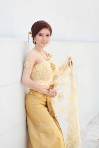 Portrait of smiling young woman standing against wall