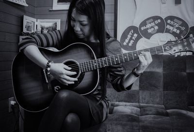 Full length of young woman playing guitar