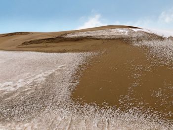 Sand dunes in desert against sky