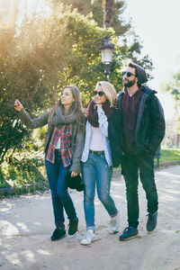 Full length portrait of happy young woman standing on mobile phone