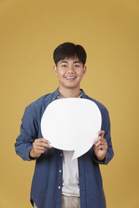 Portrait of a smiling young man against yellow background