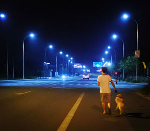 Rear view of two people walking on road at night