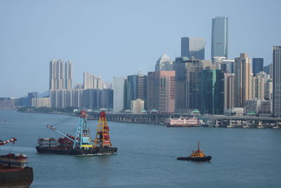 Nautical vessel on sea by buildings against clear sky