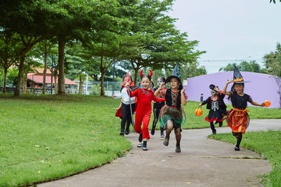 Girls in halloween costumes running on footpath at park