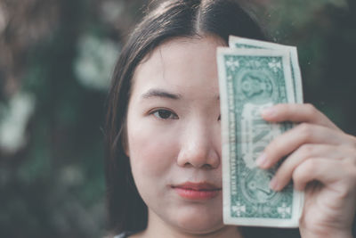 Close-up portrait of young woman holding paper currency