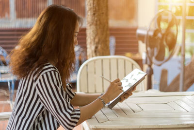 Side view of businesswoman using digital tablet at table