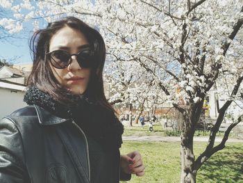 Portrait of woman standing by tree on field