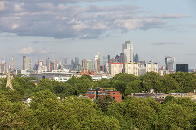 Trees and buildings in city against sky