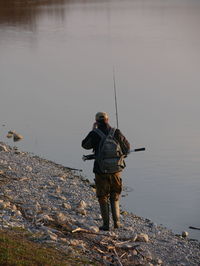 Rear view of a man with fishing road by the lake