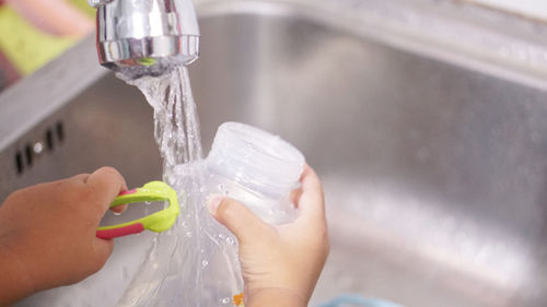 Midsection of woman drinking water from faucet