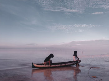 Men in boat on sea against sky