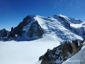 Scenic view of snowcapped mountains against clear blue sky