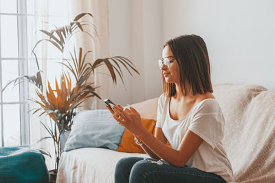 Young woman using laptop while sitting on sofa at home
