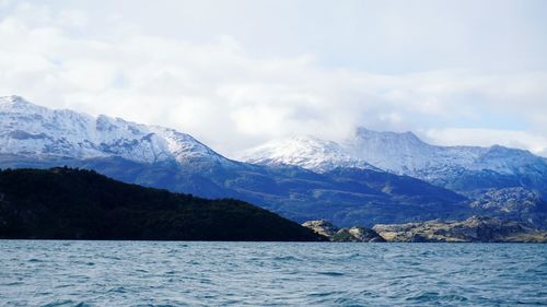 Scenic view of sea and snowcapped mountains against sky