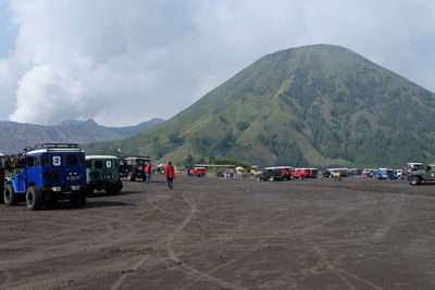 Group of people on road by mountain against sky