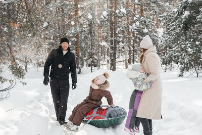 Cheerful family on a weekend rides a sleigh in a snowy forest. high quality photo