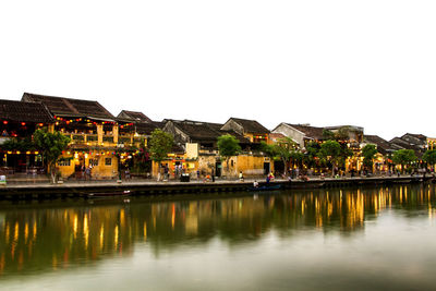 Houses by lake in town against clear sky