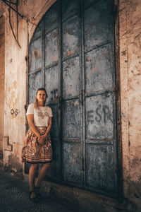 Portrait of woman standing against door