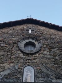 Low angle view of cross on building against clear sky