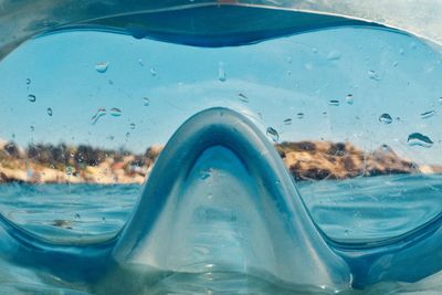 Close-up of wet mask against blue sea