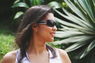 Close-up of young woman wearing sunglasses against plants