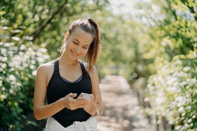 Beautiful young woman using mobile phone outdoors