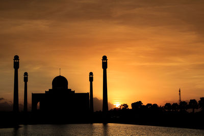 Silhouette of buildings against cloudy sky during sunset