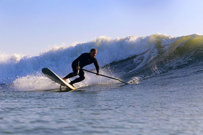 Male sup surfer at sunset time