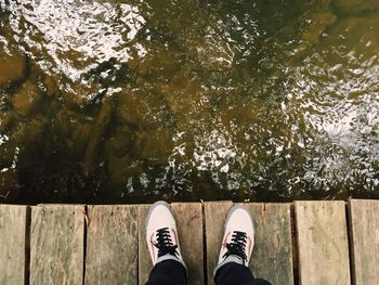 Low section of man standing by lake