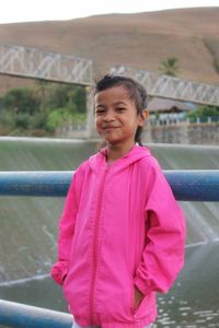 Portrait of young man standing against railing