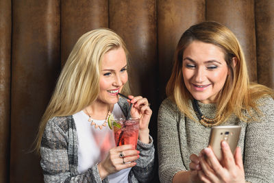 Happy women using smartphone in pub