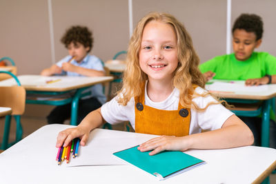 Portrait of smiling girl sitting on table