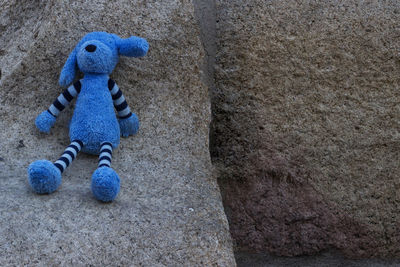 Close-up of toy on rock against wall