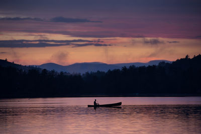 Silhouette boat in lake against sky during sunset