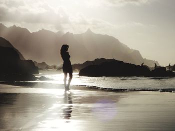 Silhouette man standing on beach against sky