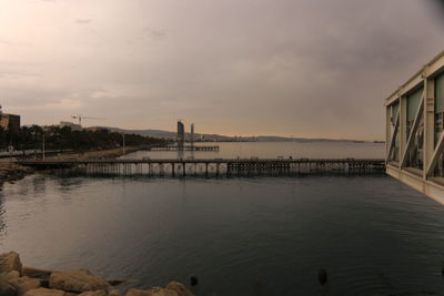 Pier over river against cloudy sky