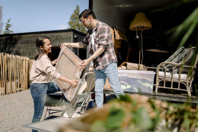 Man and woman unloading painting from truck during sunny day