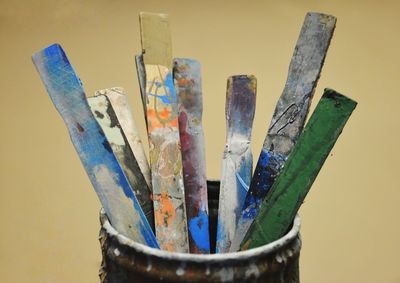 Close-up of paintbrushes in container against colored background