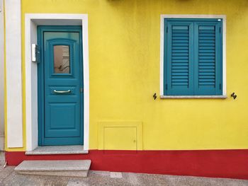 Closed blue door of yellow house
