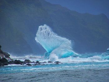 Huge wave splashing in sea against mountain