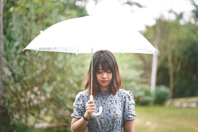 Mid adult woman holding umbrella while standing outdoors