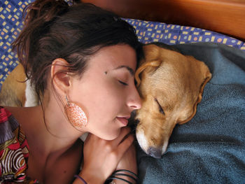 High angle view of woman with dog sleeping on bed at home